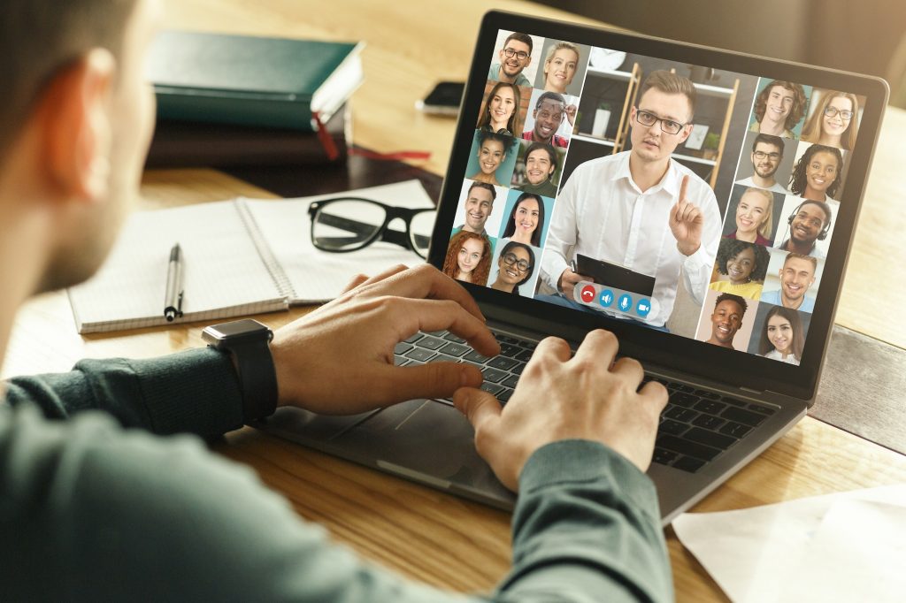 Back view of male employee having video conference on laptop with colleagues